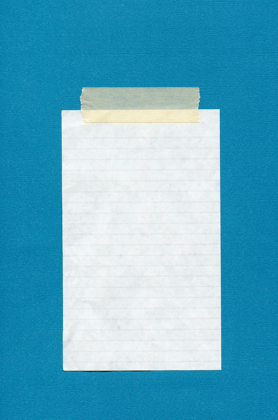 Blank lined paper attached with masking tape to a teal background.
