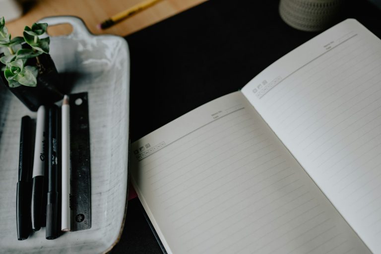 Open notebook and pens on a desk.